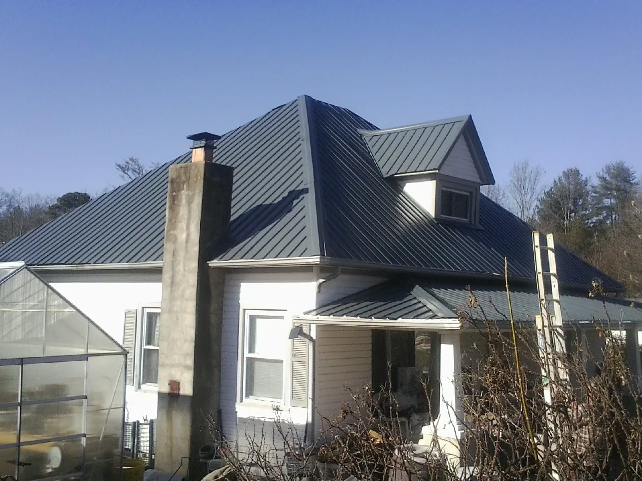Dark blue standing seam metal roof on a white farmhouse with dormer — Slate & Tile Roof Repair by Roofing Brothers in Edinboro