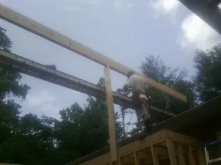 Carpenter setting a ridge beam over a new addition frame — Ice Dam Removal by Roofing Brothers in Edinboro