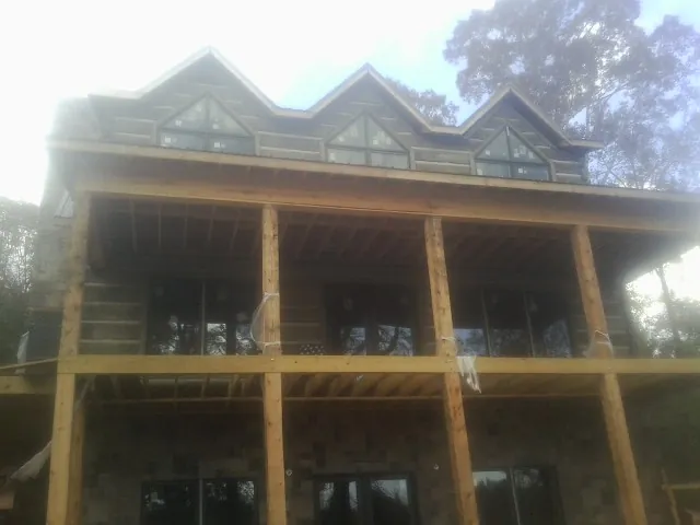 Dormers and porch framing on a large log home under construction — Roof Coating work by our crew in Edinboro