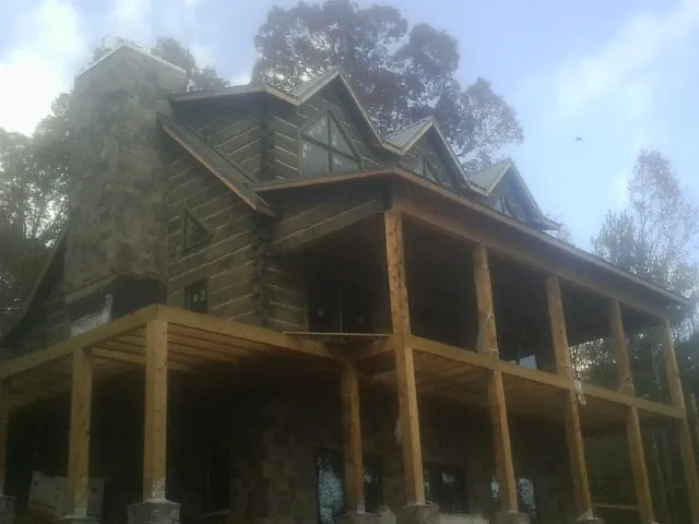Stone chimney and dormers on a large log home with a timber porch in Edinboro