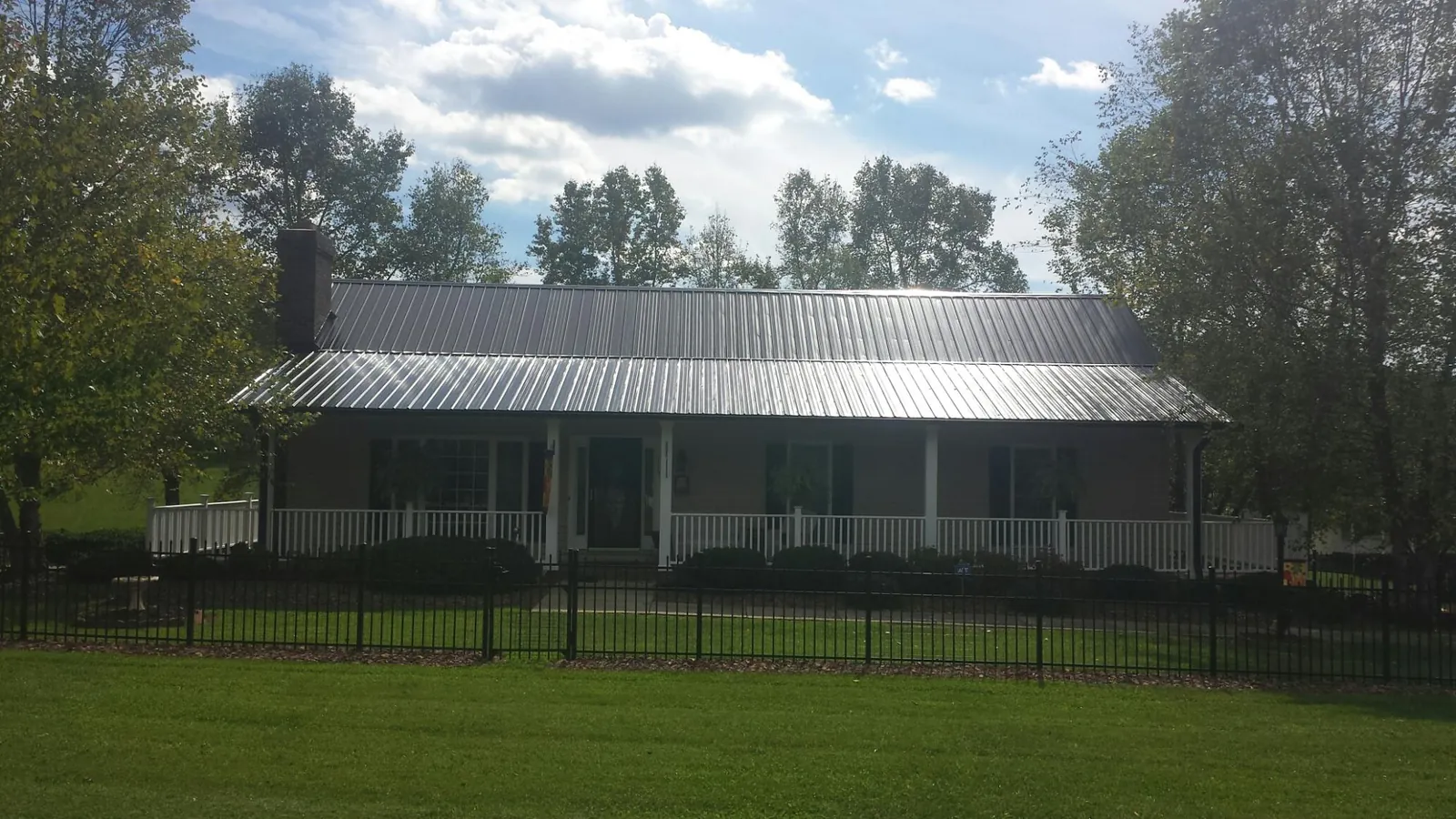 Gray metal roof on a brick ranch with a full width front porch — Gutter Guard Installation work by our crew in Edinboro