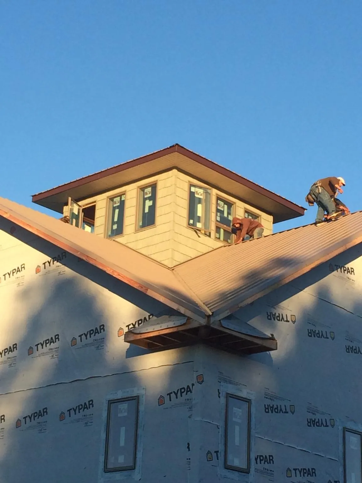 Roofers working around a rooftop cupola on a new metal roof at sunset — Roof Waterproofing in Edinboro by Roofing Brothers